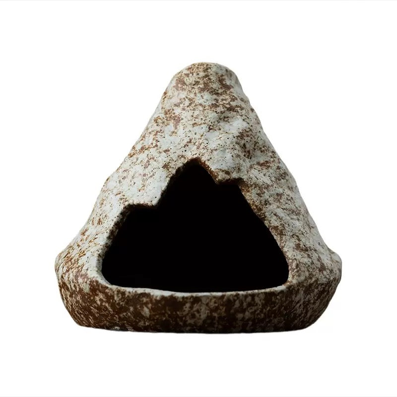 Handmade ceramic incense burner in a cave-inspired triangular stone shape, featuring a rustic speckled surface and hollow center, displayed on a clean white background.