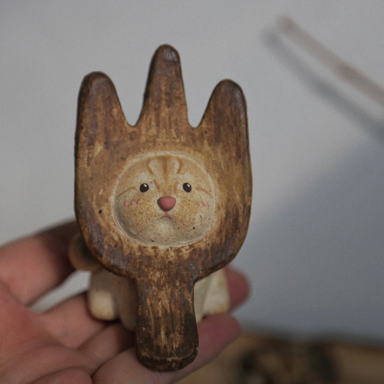 Handmade ceramic incense holder shaped like The Hungry Foodie Cat shown held in hand, featuring a fork-inspired design and hand-painted cat face