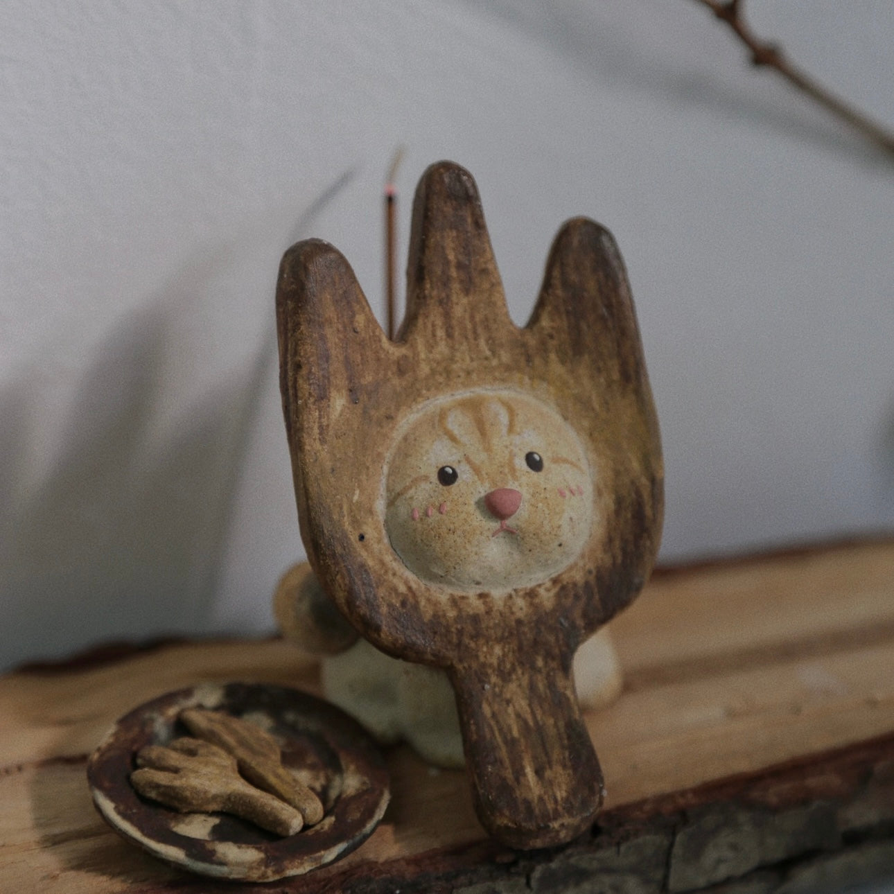 Handmade ceramic incense holder shaped like The Hungry Foodie Cat displayed on a wooden surface with a matching ash tray and incense stick in a lifestyle setting