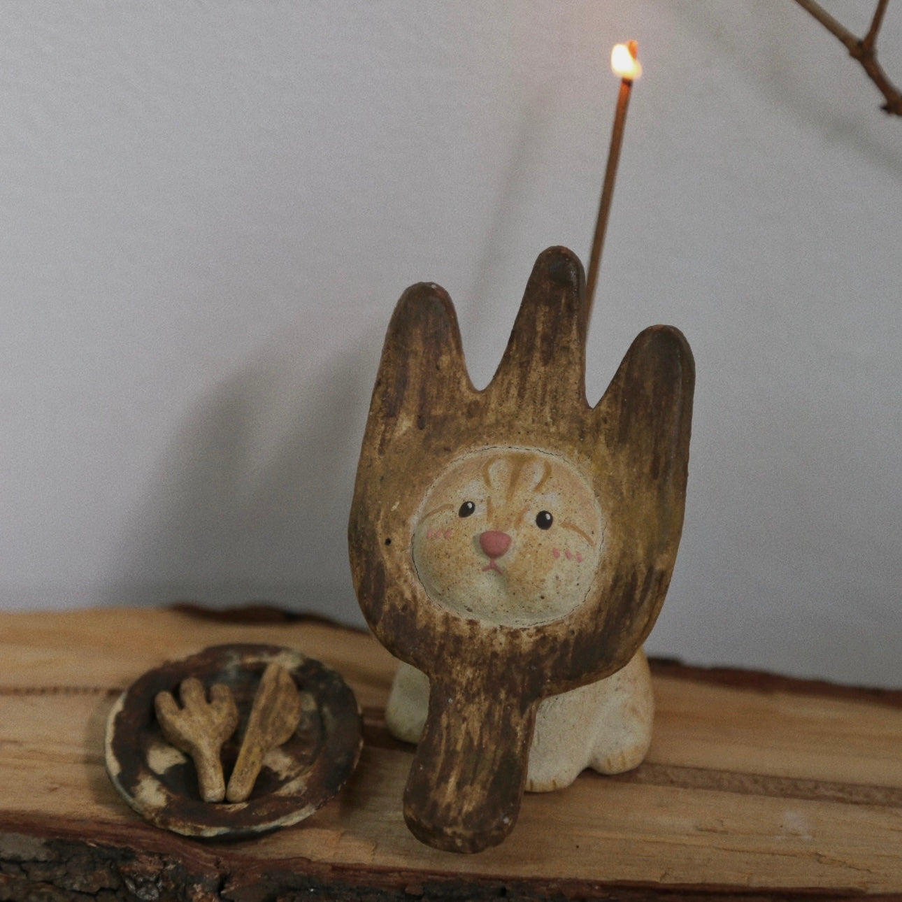 Handmade ceramic incense holder shaped like The Hungry Foodie Cat with a lit incense stick and matching ash tray on a rustic wood surface