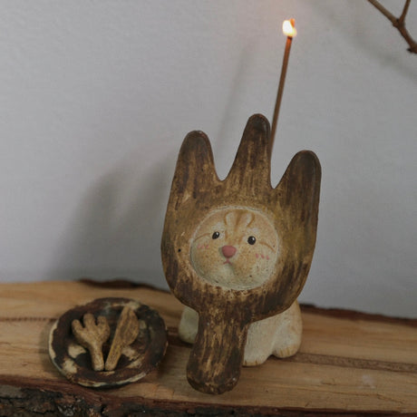 Handmade ceramic incense holder shaped like The Hungry Foodie Cat with a lit incense stick and matching ash tray on a rustic wood surface