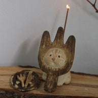 Handmade ceramic incense holder shaped like The Hungry Foodie Cat with a lit incense stick and matching ash tray on a rustic wood surface