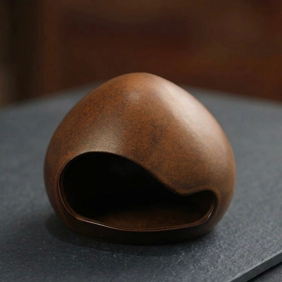 Bottom view of a handmade ceramic yawning face incense burner showing the hollow base opening and rounded ceramic shape