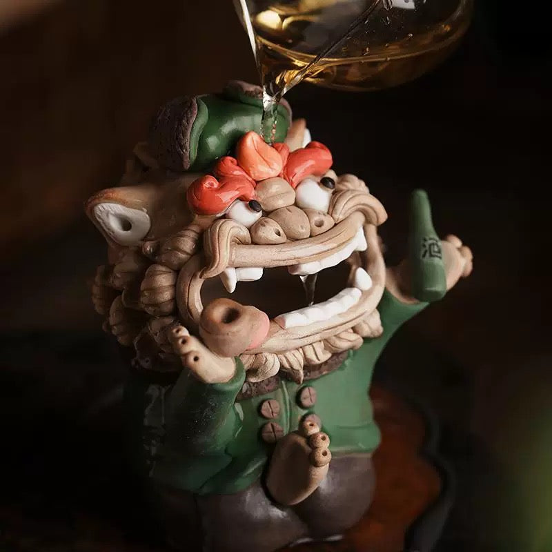 Close-up of the handmade quirky ceramic incense holder shaped like a green lion figure holding a pipe and bottle in a warm moody indoor setting
