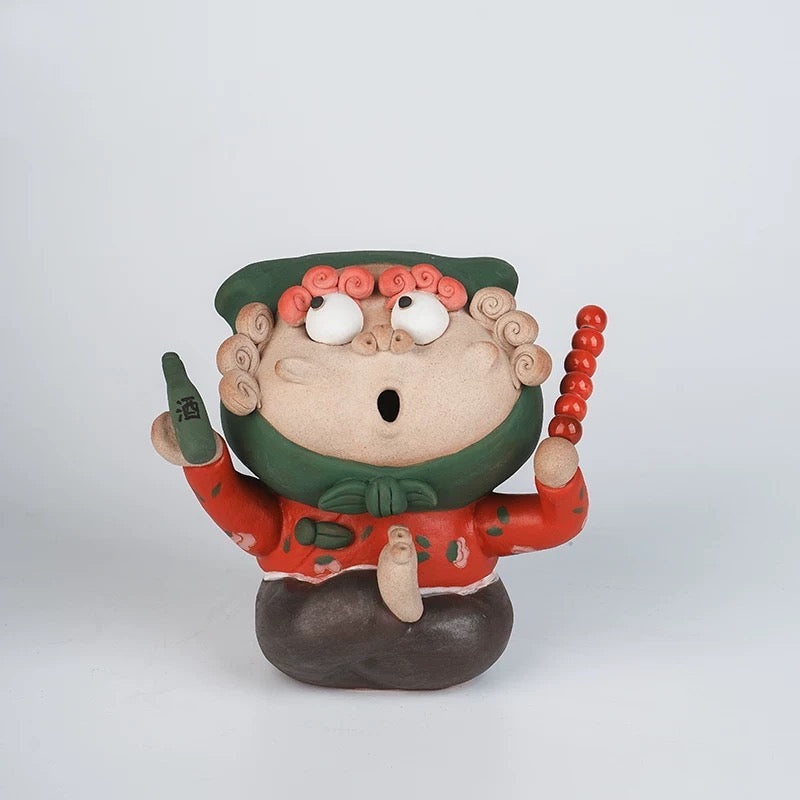 Handmade quirky ceramic incense holder shaped like a red figure holding a bottle and skewer on a white background
