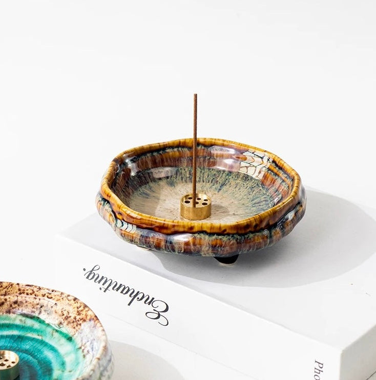 Handmade Japanese wabi-sabi style ceramic incense holder with warm brown crackle glaze and a brass incense insert on a white background.
