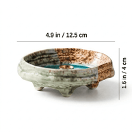 Japanese wabi-sabi style green ceramic incense holder with crackle glaze and three feet, showing size dimensions 4.9 in wide and 1.6 in high on a white background.