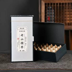 Laoshan agarwood backflow incense cones in a black box with white packaging beside an open tray of cones for waterfall incense burner