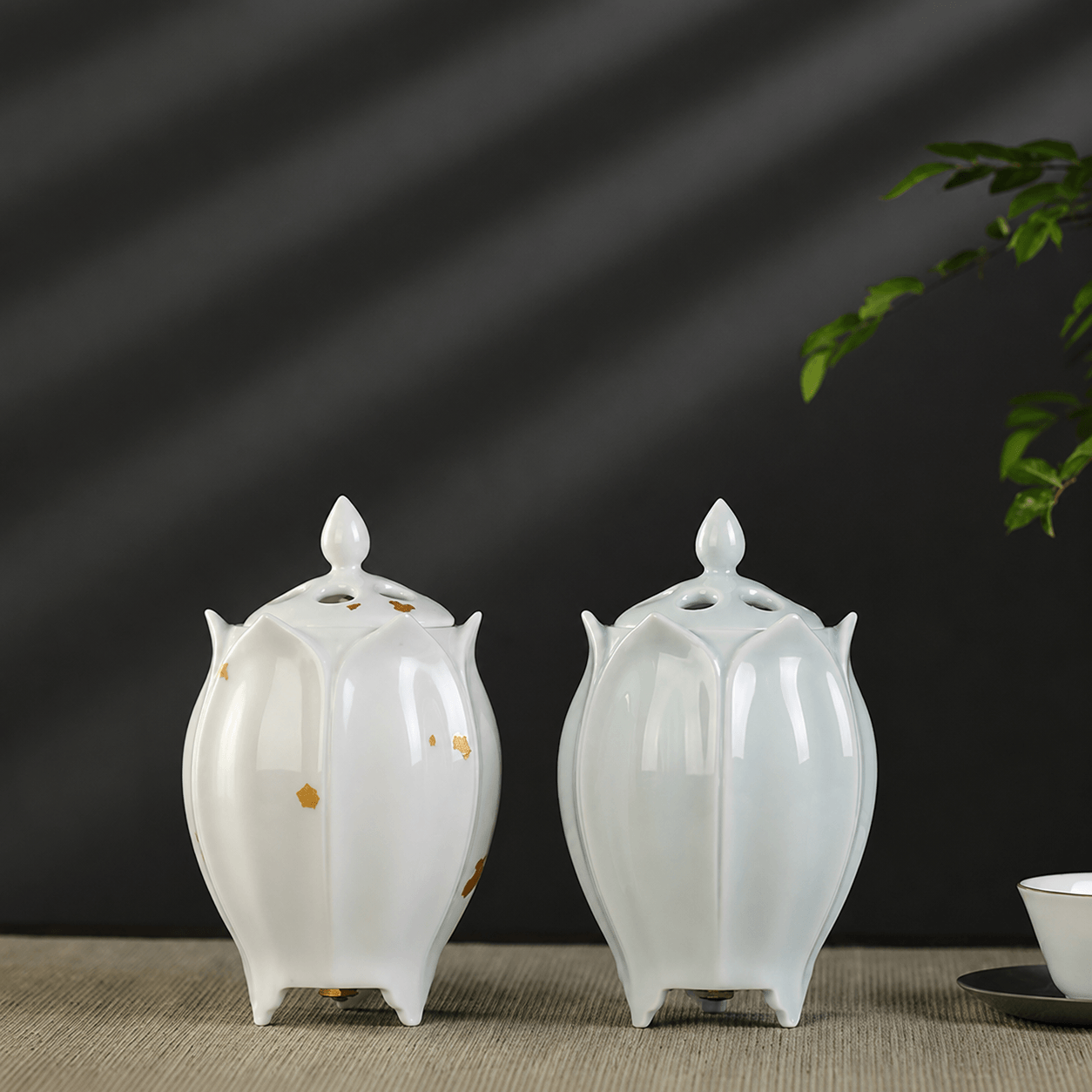 Two lotus shaped electric ceramic incense burners displayed together showing the green and white color options on a tabletop
