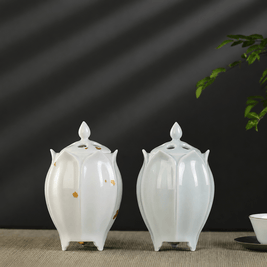 Two lotus shaped electric ceramic incense burners displayed together showing the green and white color options on a tabletop