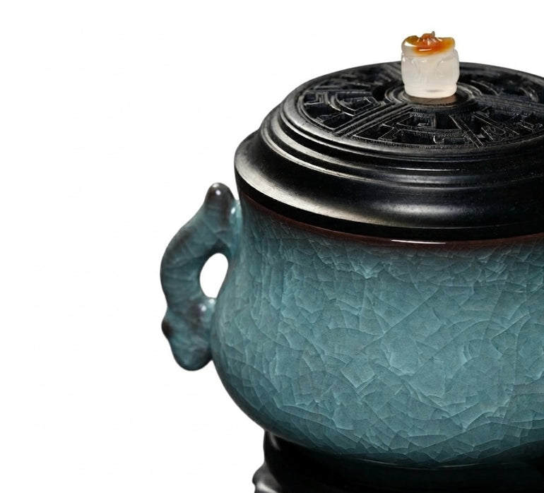 Close-up of a luxury electric incense burner with a Ge kiln ice-crackle ceramic body, black lid, and decorative side handle