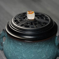 Close-up of a luxury electric incense burner with a Ge kiln ice-crackle ceramic body, carved black lid, and side handles