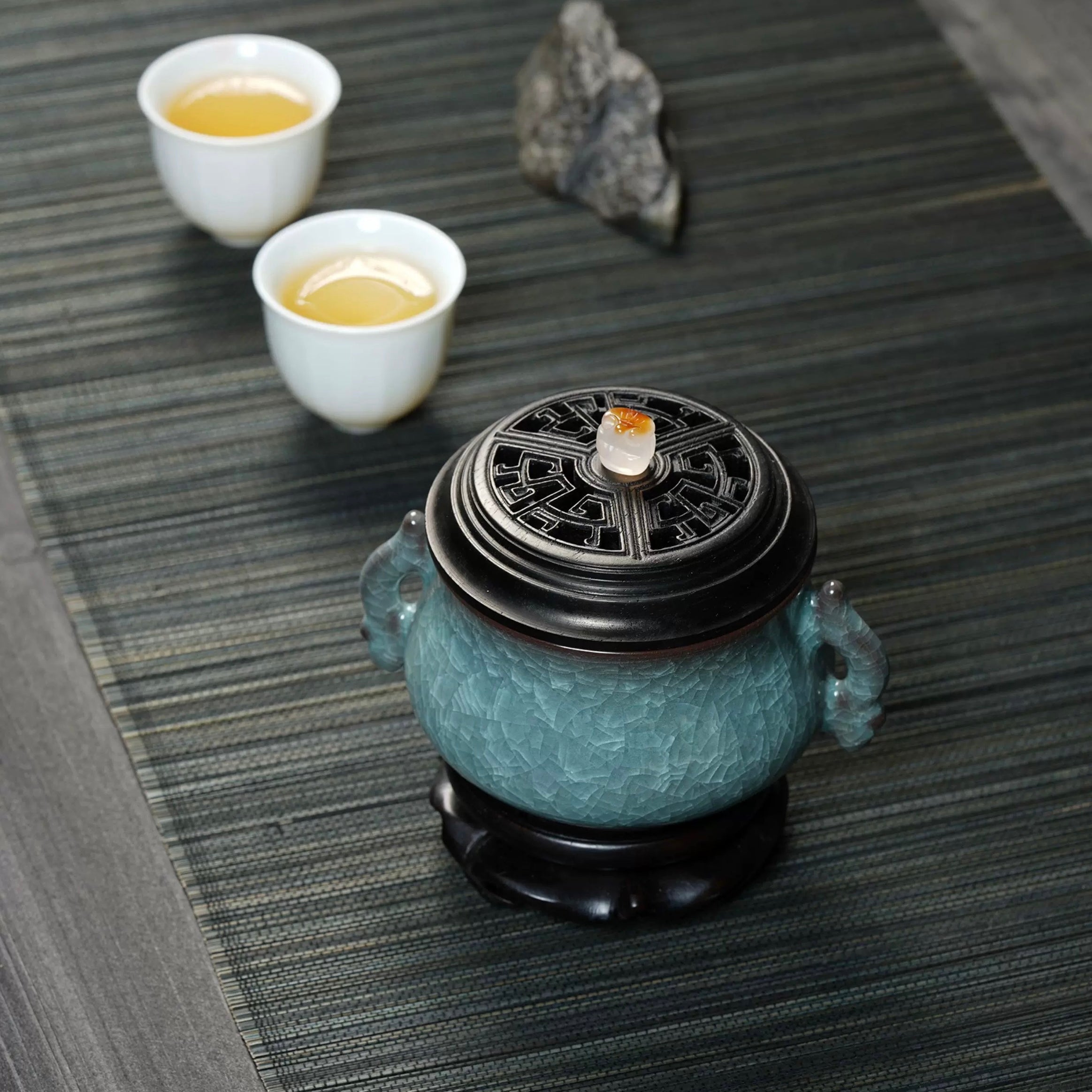 Luxury electric incense burner on a tea table with two teacups, featuring a Ge kiln ice-crackle ceramic body, black lid, and decorative base