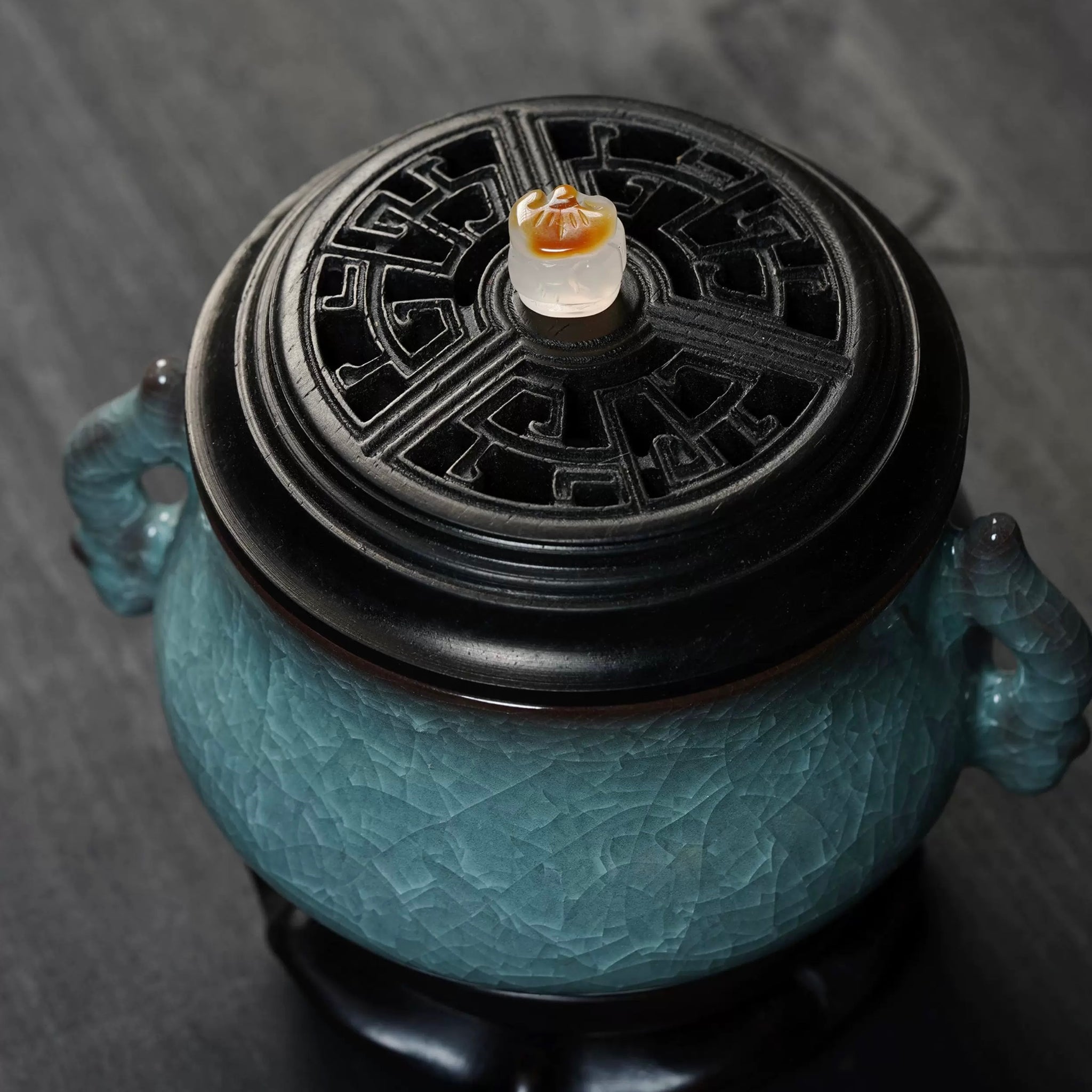 Top view of a luxury electric incense burner with a Ge kiln ice-crackle ceramic body, black lid, and twin side handles