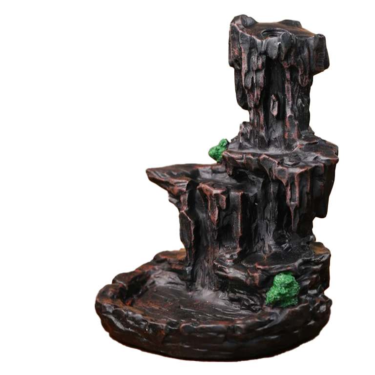 Mountain waterfall backflow incense burner in dark rock-like ceramic, featuring stacked cliff tiers, a shallow basin base, and small green moss accents on a white background.