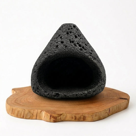 Black cave-shaped natural stone incense burner with a porous textured surface, displayed on an organic wooden tray against a clean white background.
