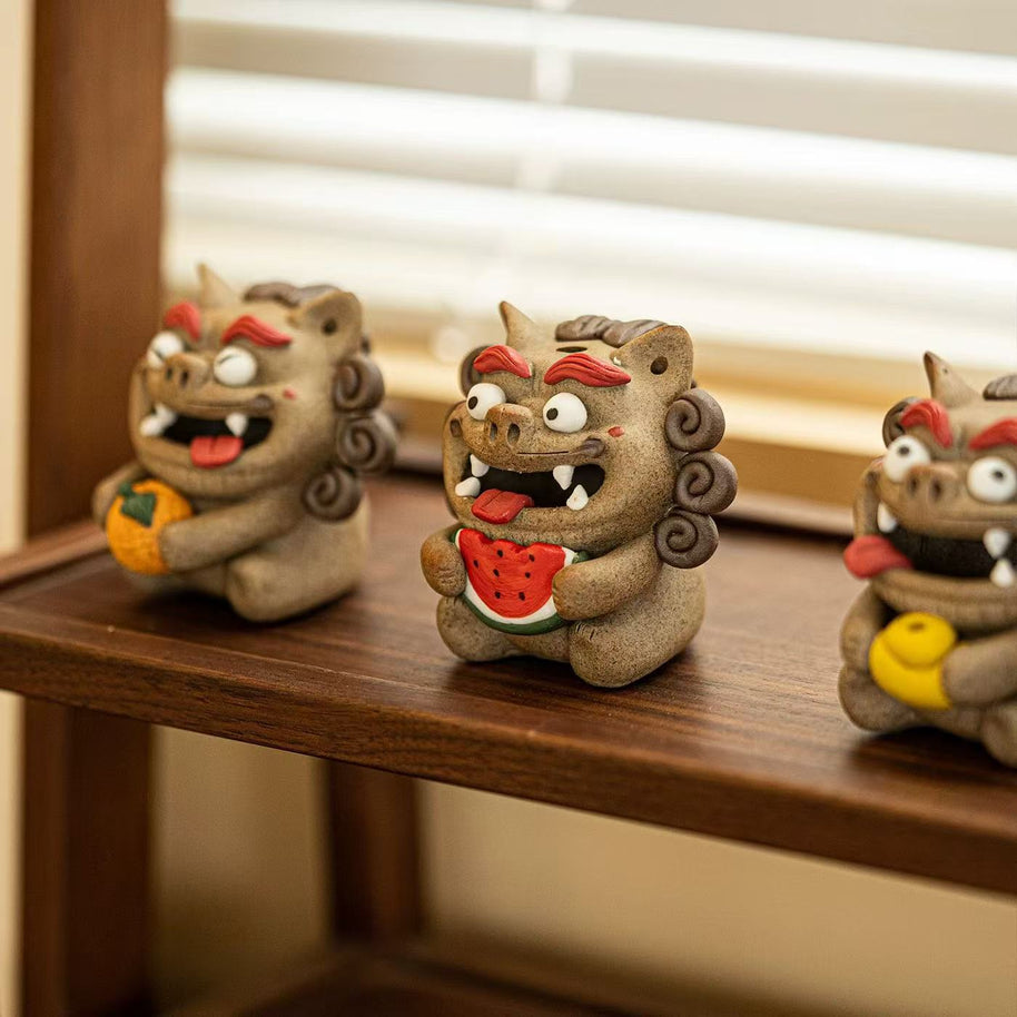 A lineup of four Pixiu backflow incense burners on a black tray, with the front‑right figure clutching a watermelon slice in clear focus, its open mouth emitting a mist‑like cascade, and three other Pixiu figures softly blurred behind.