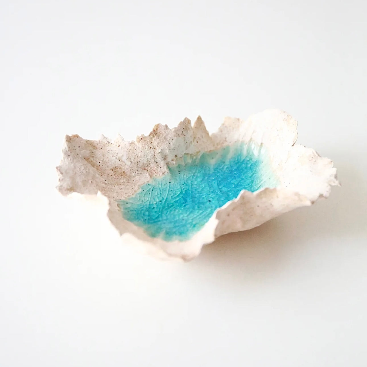 Sea Blossom handmade ceramic incense and candle holder with an organic coral-inspired shape and blue lagoon glaze center, shown empty on a clean white background