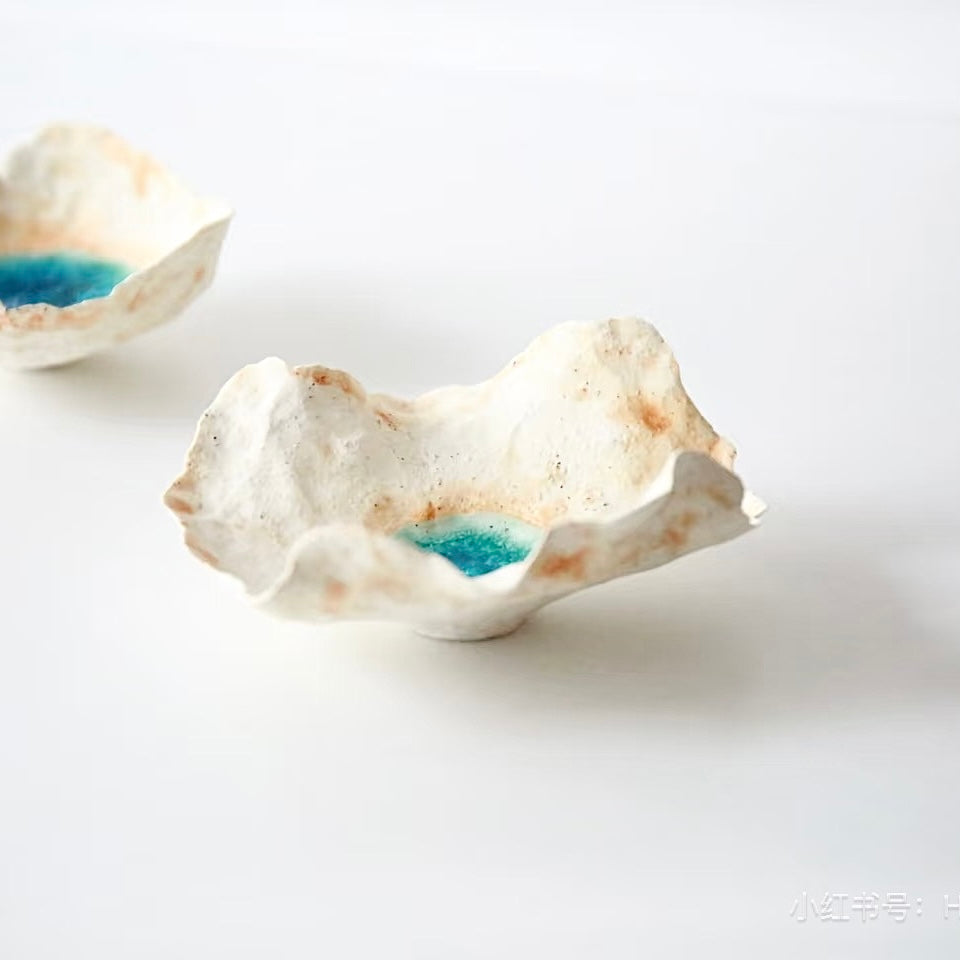 Angled detail view of the Sea Blossom handmade ceramic incense holder with organic shell-like edges, textured white clay finish, and a vivid blue glaze center on a clean white background