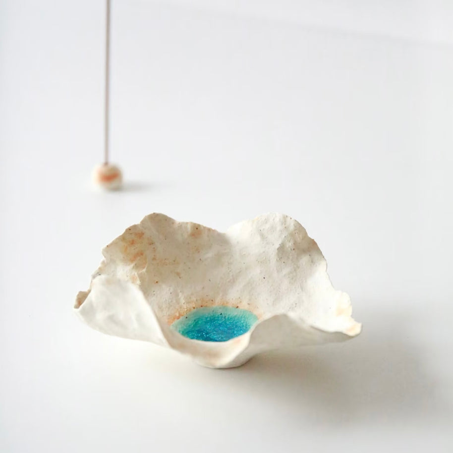 Sea Blossom handmade ceramic incense holder with sculpted organic white clay edges and a bright blue glaze center, shown in a minimalist studio setting with incense accessory softly blurred in the background