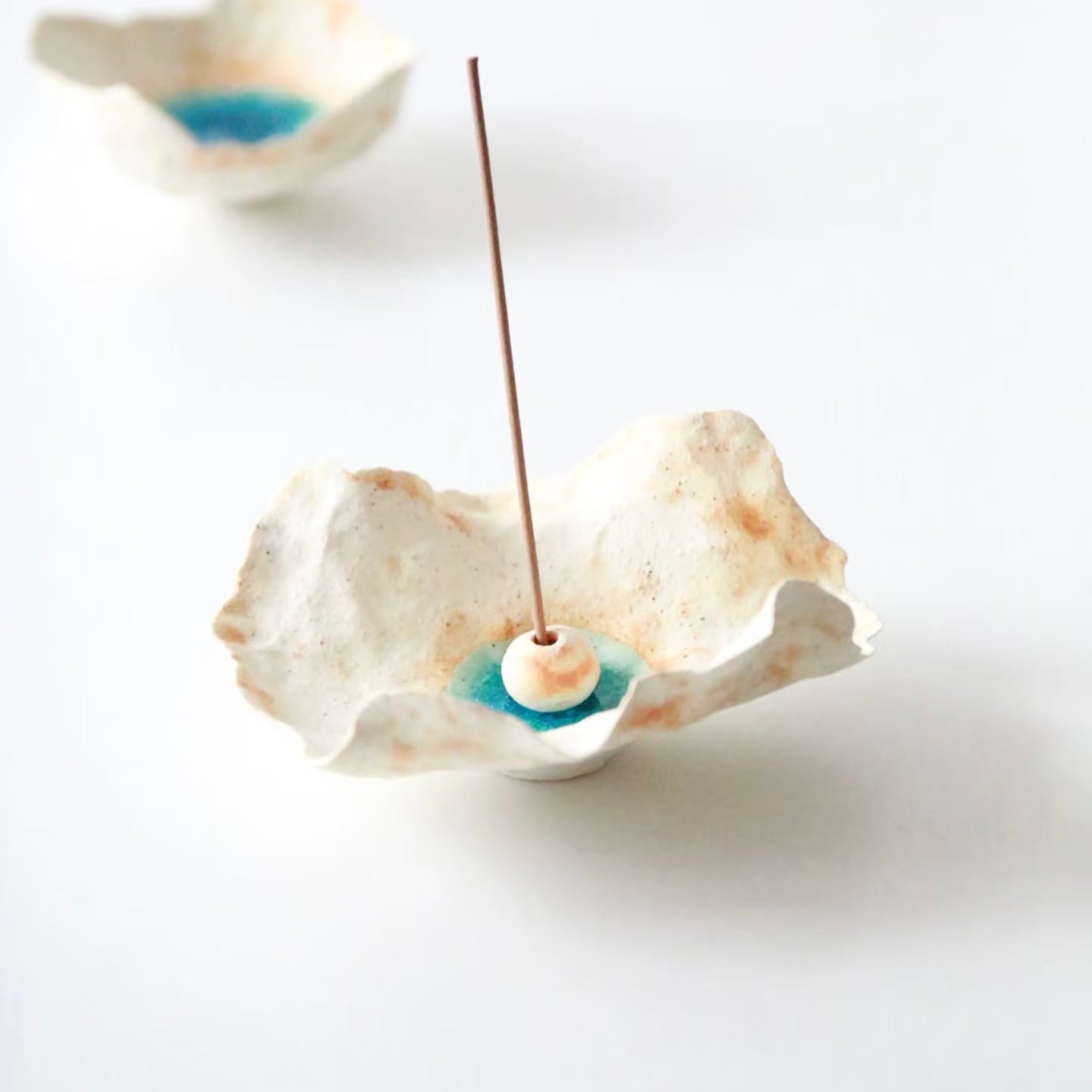 Sea Blossom handmade ceramic incense holder with organic sculpted edges, blue glaze center, and white ceramic bead, displayed with an incense stick on a clean white background