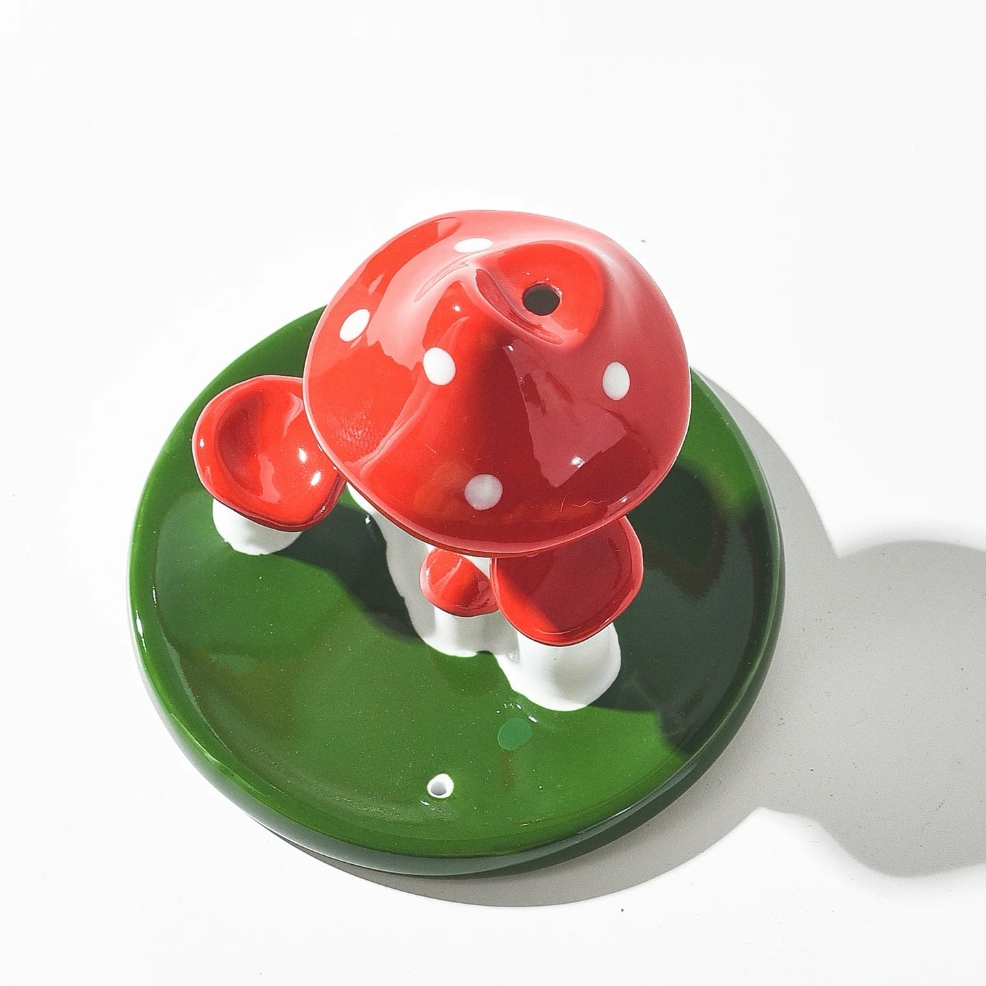 Overhead view showing the circular vent on the red mushroom cap and the small hole on the green base for incense sticks