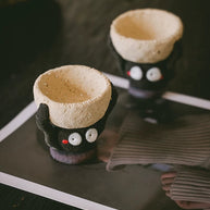 Two handmade ceramic Soot Spirit candle holders with textured cream bowls displayed on a table.