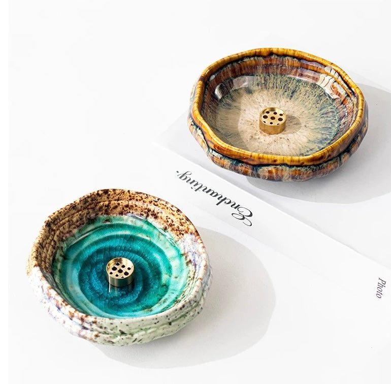 Two handmade wabi-sabi ceramic incense holders, one green and one brown with crackle glaze and brass incense inserts, displayed on a white background.