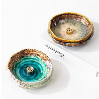 Two handmade wabi-sabi ceramic incense holders, one green and one brown with crackle glaze and brass incense inserts, displayed on a white background.