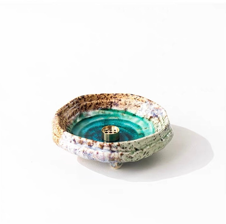 Handmade wabi-sabi ceramic incense holder with green crackle glaze and brass incense insert on a white background.