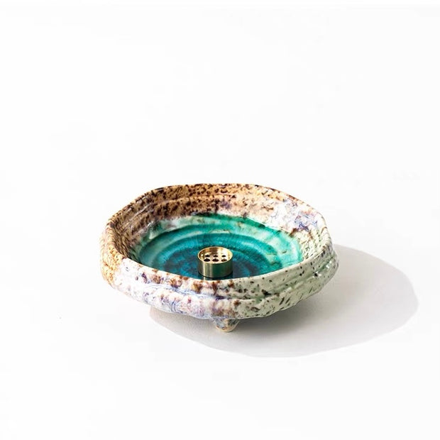 Handmade wabi-sabi ceramic incense holder with green crackle glaze and brass incense insert on a white background.