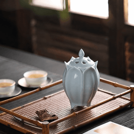 White lotus shaped electric ceramic incense burner displayed on a bamboo tray beside tea cups and incense wood