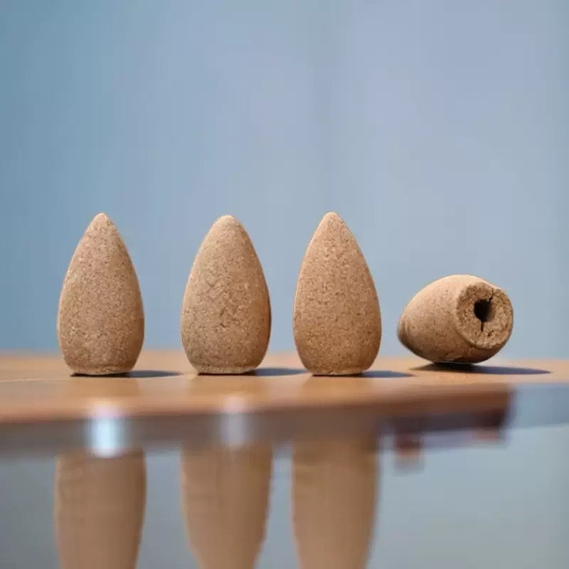 Close up of wormwood backflow incense cones with three standing upright and one lying on its side showing the hollow base for waterfall incense burner