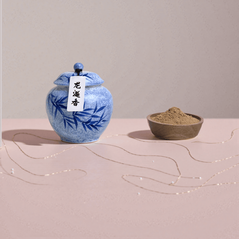 Ambergris handcrafted natural incense powder stored in a blue ceramic jar, with a small amount placed in a wooden bowl to show the powder.