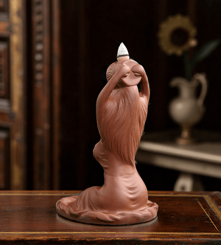 Side view of the ceramic goddess-shaped backflow incense burner, showing incense cone placement and flowing sculptural details.