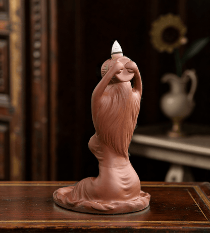 Side view of the ceramic goddess-shaped backflow incense burner, showing incense cone placement and flowing sculptural details.