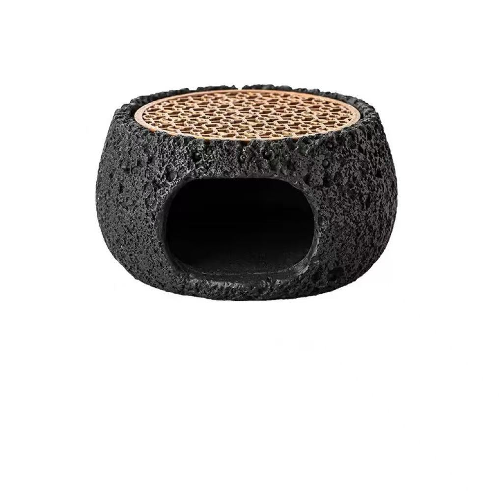 Top view of black cement incense burner featuring textured volcanic surface and rosewood grate for burning crystal or herbal incense
