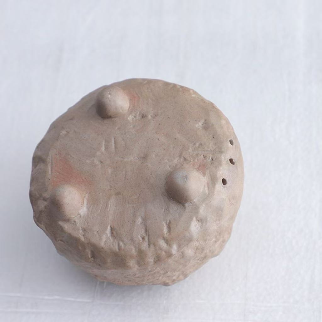 Bottom view of handmade ceramic incense burner showing three rounded feet and ventilation holes, crafted with a textured natural clay finis