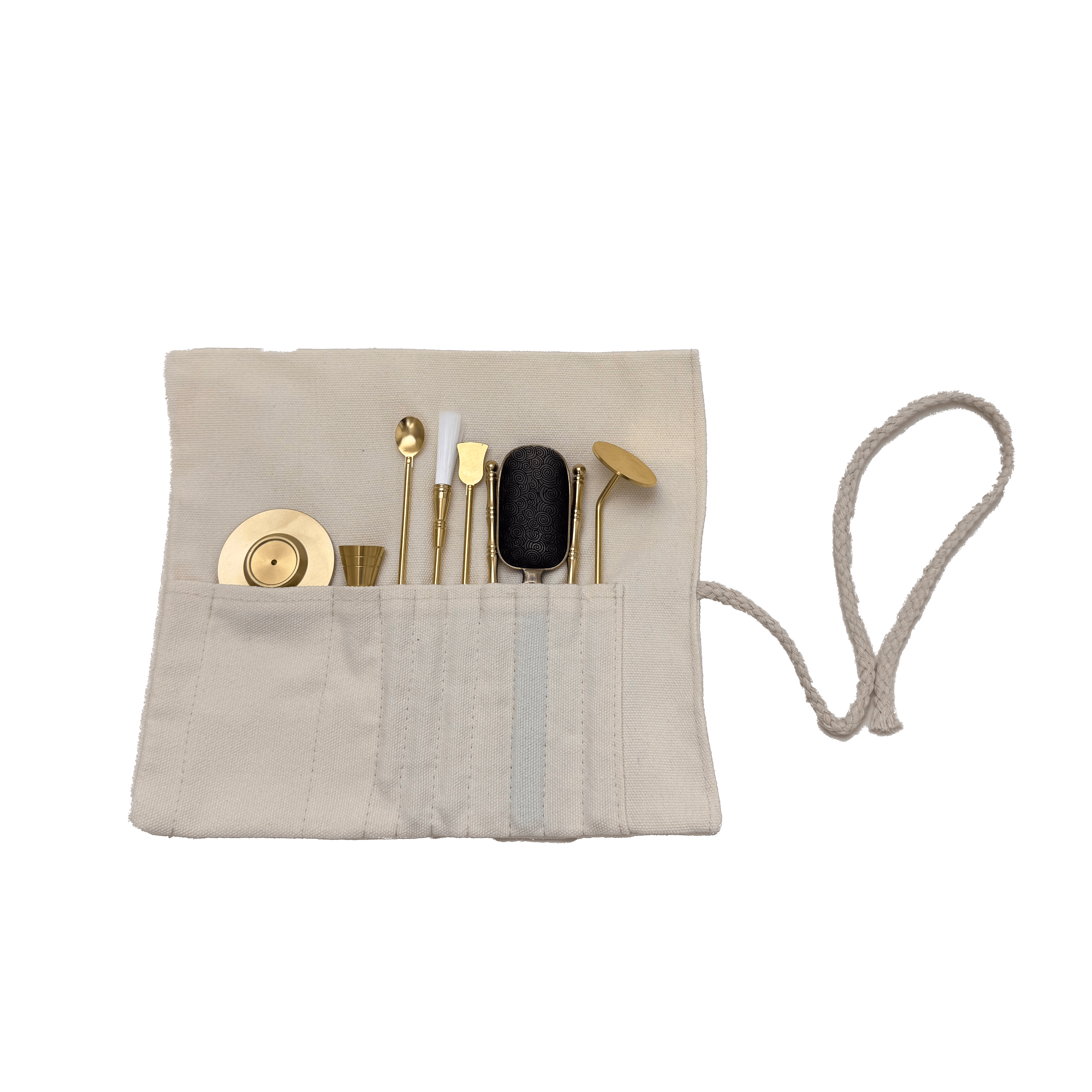 Top view of brass incense tool kit neatly arranged in cotton storage wrap, showing spatulas, tongs, press, and spoon tools on transparent background