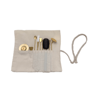 Top view of brass incense tool kit neatly arranged in cotton storage wrap, showing spatulas, tongs, press, and spoon tools on transparent background