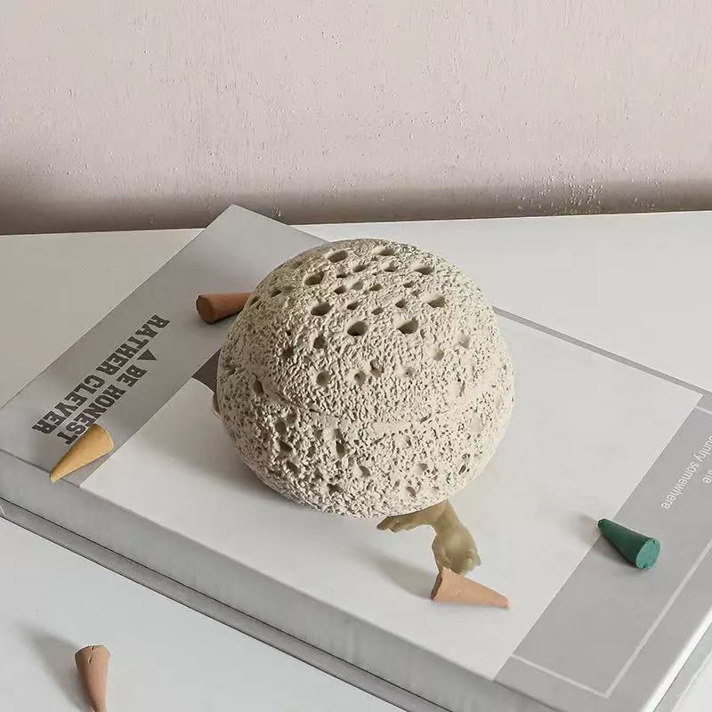 Cement incense burner lid placed on minimal book stack with colorful cone incense around, showcasing natural texture and earthy aesthetic