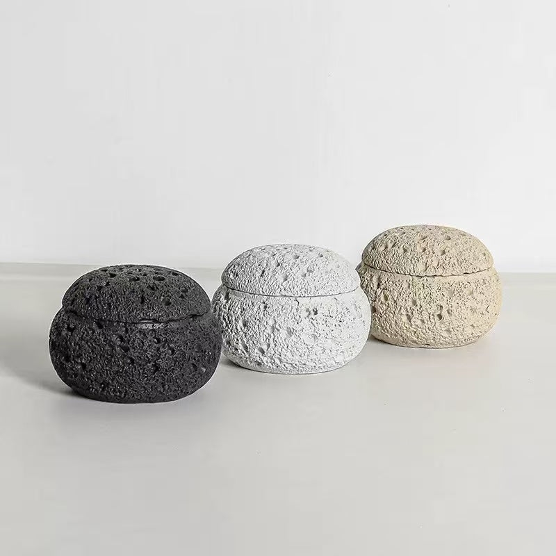 Three dome-shaped handmade cement incense burners in black, white, and off-white colors, shown side by side on a white background