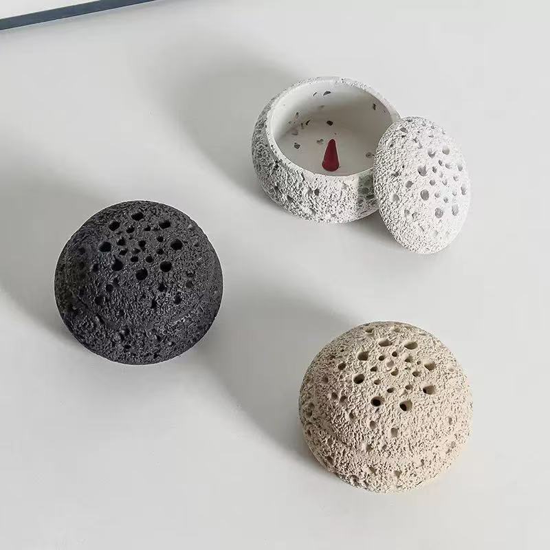 Three handmade cement incense burner lids in black, white, and off-white colors, displayed beside matching base with cone incense