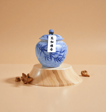 Dongjia sandalwood incense powder in a blue ceramic jar, made from pure Tongan sandalwood, shown with powdered form on a wooden base.