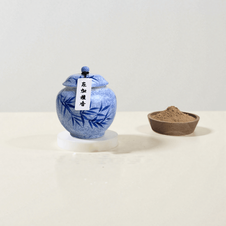 Dongjia handcrafted natural incense powder in a blue ceramic jar, with some placed in a bowl to show the powder’s form, made from pure Tongan sandalwood.