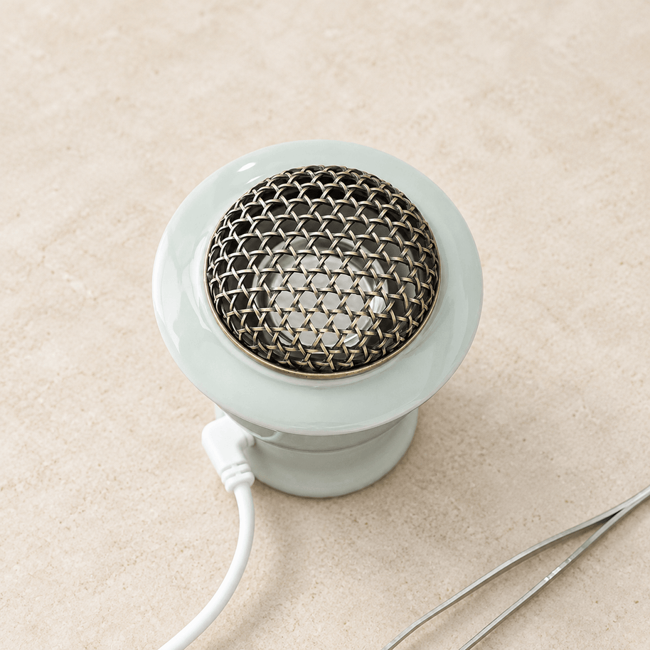 Top view of the celadon green electric incense burner showing its domed metal mesh cover and attached white power cord.