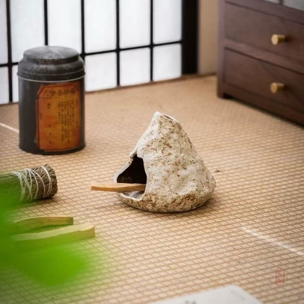 Handmade ceramic incense burner displayed with stick incense, green incense string roll, and a vintage tea canister on a tatami mat background in a traditional Japanese-style room