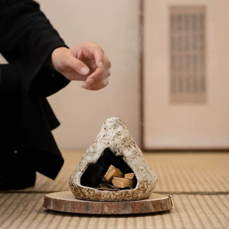 Handmade ceramic incense burner with pine wood tray placed on a tatami mat, featuring natural stone-like texture and burning incense pieces inside.