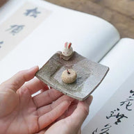 Handmade ceramic incense holder with rabbit figurine, shown in hand for size reference, artisanal incense burner for meditation and home decor.
