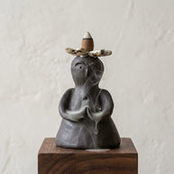 Side view of a handmade ceramic backflow incense holder with smoke flowing through the sculptural figure.